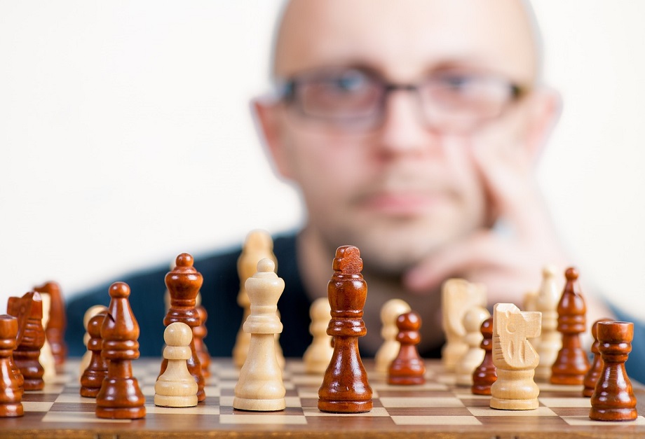 チェスの盤面を見つめる男性